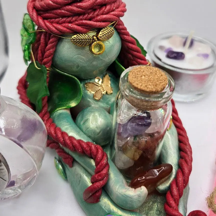 Detail of handmade Aisling Brigid figurine with crystal vial, carnelian and botanical leaf symbolism
